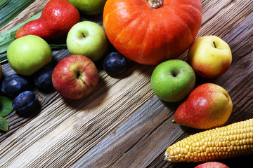 Various fresh fruits. Thanksgiving pumpkin, apples, and maize on rustic background.