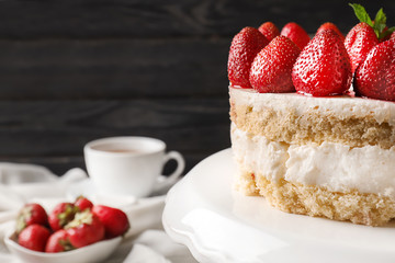 Delicious cake with strawberries on stand