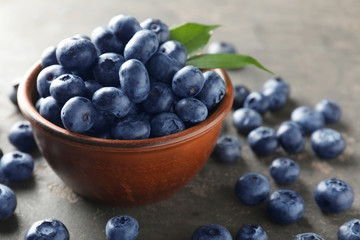 Bowl with ripe blueberries on grey background