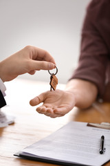 Real estate agent giving key of new house to man in office