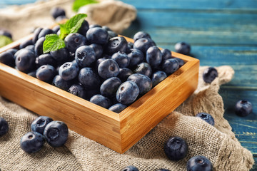 Wooden box with ripe blueberries on table