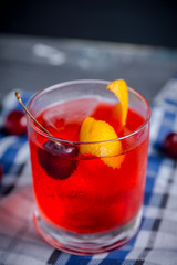 Old fashioned cocktail with cherry and orange peel. Selective focus.