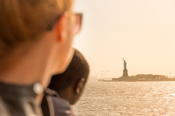 Tourists looking at Statue of Liberty silhouette in sunset from the staten island ferry, New York City, USA. © kasto