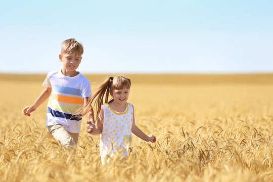 Cute Little Children Running In Wheat Field On Summer Day