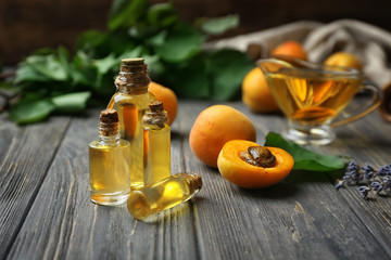 Bottles of apricot essential oil on wooden table