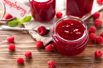 Jar with tasty raspberry jam on wooden table