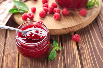 Jar with tasty raspberry jam on wooden table