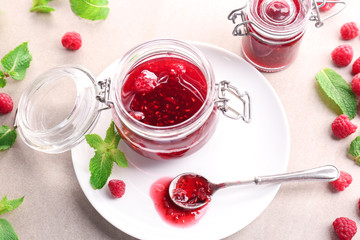 Jar with tasty raspberry jam on plate