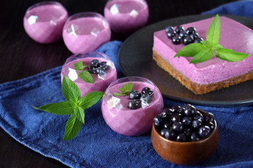 Portions of berry mousse dessert and cake topped with bilberries and mint 