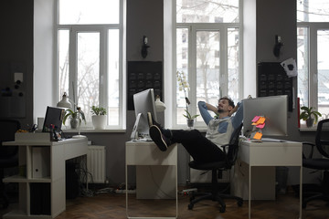 A man thinking of a vacation in a modern office while relaxing