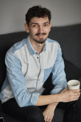 Freelancer resting with a cup of coffee on a couch while thinkin