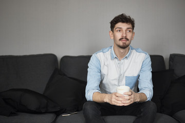 Freelancer resting with a cup of coffee on a couch while thinkin