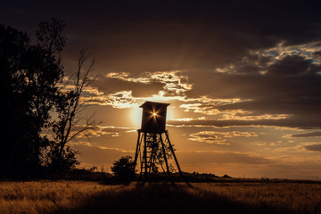 Naklejka premium Hunters Lookout Tower on Sunset Field. Beautiful Landscape. Nature Scene in Czech Republic, Europe.