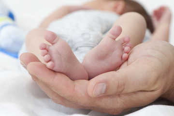 Stopy niemowlaka w dłoniach ojca. - obrazy, fototapety, plakaty