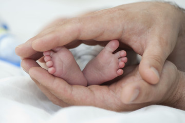 Stopy noworodka w dłoniach ojca.