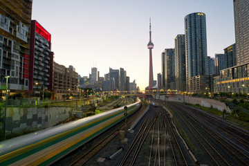 Train in downtown of Toronto with highrise buildings and CN Tower at sunset