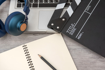 office stuff with Movie clapper laptop and pen notepad on the wood table top view shot.dark effect