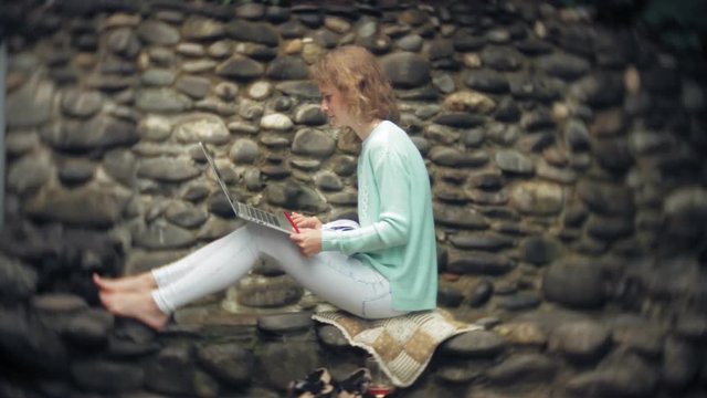 Woman with laptop and documents on the background of a stonewall wall