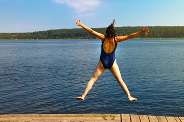 girl jumping into the water from a wooden pier