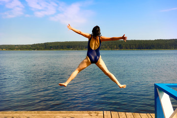 girl jumping into the water from a wooden pier