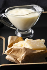 Sauce Bechamel. Parmigiano cheese in rough paper on a black table. Italian food.
