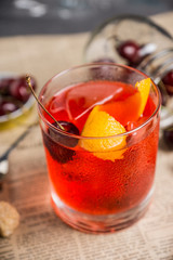 Old fashioned cocktail with cherry and orange peel. Selective focus.