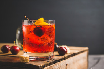 Old fashioned cocktail with cherry and orange peel. Selective focus.