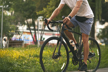 De jonge man in vrijetijdskleding fietst op de weg in de avondstad