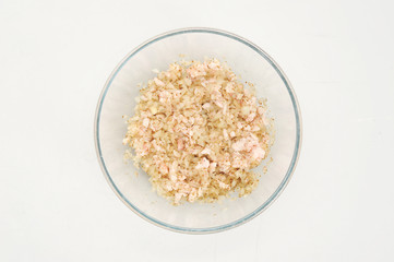 In a deep bowl, the onions are mixed with spices and fat. White background. Close-up. View from above.