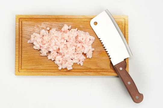 Finely chopped Kurdyuk-mutton fat on a light wooden board. Then a knife for cutting. White background. Close-up. View from above.