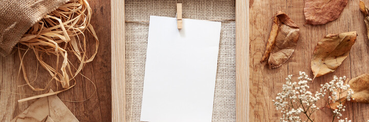 Panoramic mockup frame with white flowers in a vase with old envelopes, a leaf and a jute bag