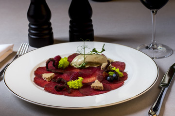 carpaccio with deer served on white plate, decorated