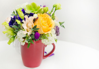 Spring flowers in red cup with on white background.