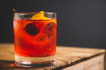 Old fashioned cocktail with cherry and orange peel. Selective focus.