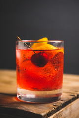 Old fashioned cocktail with cherry and orange peel. Selective focus.