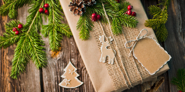 Christmas gift wrapped in kraft paper with decoration on a rustic wooden background from above. Flat style. mockup free space. Blank form
