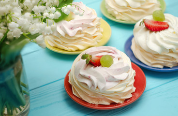 Strawberry pavlova cake nests, meringue decoration on wood table with flowers.