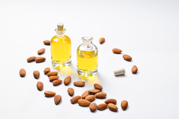 Bottles of almond oil and almonds  on white background, copyspace.