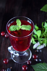 Berry kissel in a glass mug topped with mint against the dark background