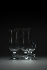 Dangerous still life with three empty modern broken / shattered glasses on a table