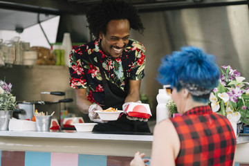 Smiling food vendor hands food to waiting customer