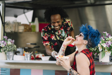 Smiling food vendor hands food to waiting customer
