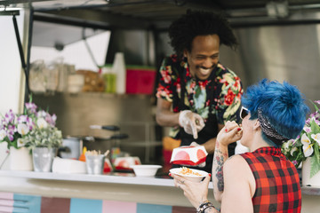 Smiling food vendor hands food to waiting customer