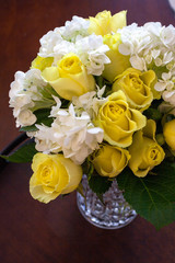 Vertical, tight shot of Yellow Roses and White Hydrangeas in a Crystal Decanter