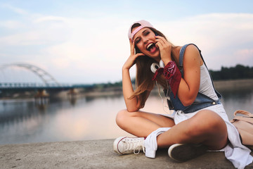 Portrait of smiling young urban woman using smart phone outdoors while waiting for her friends