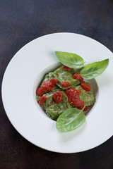 White plate with italian spinach ravioli, elevated view on a brown metal background, vertical shot