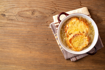 French onion soup with croutons and cheese on rustic wooden table