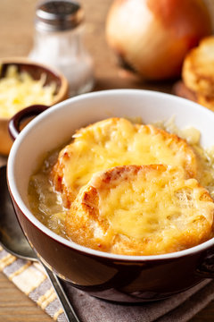French onion soup with croutons and cheese on rustic wooden table