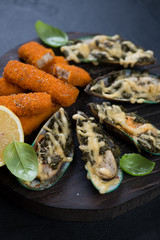 Close-up of baked mussels and roasted fish fingers, selective focus, studio shot