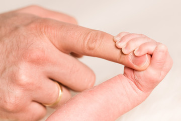 Baby greift nach Finger des Vaters